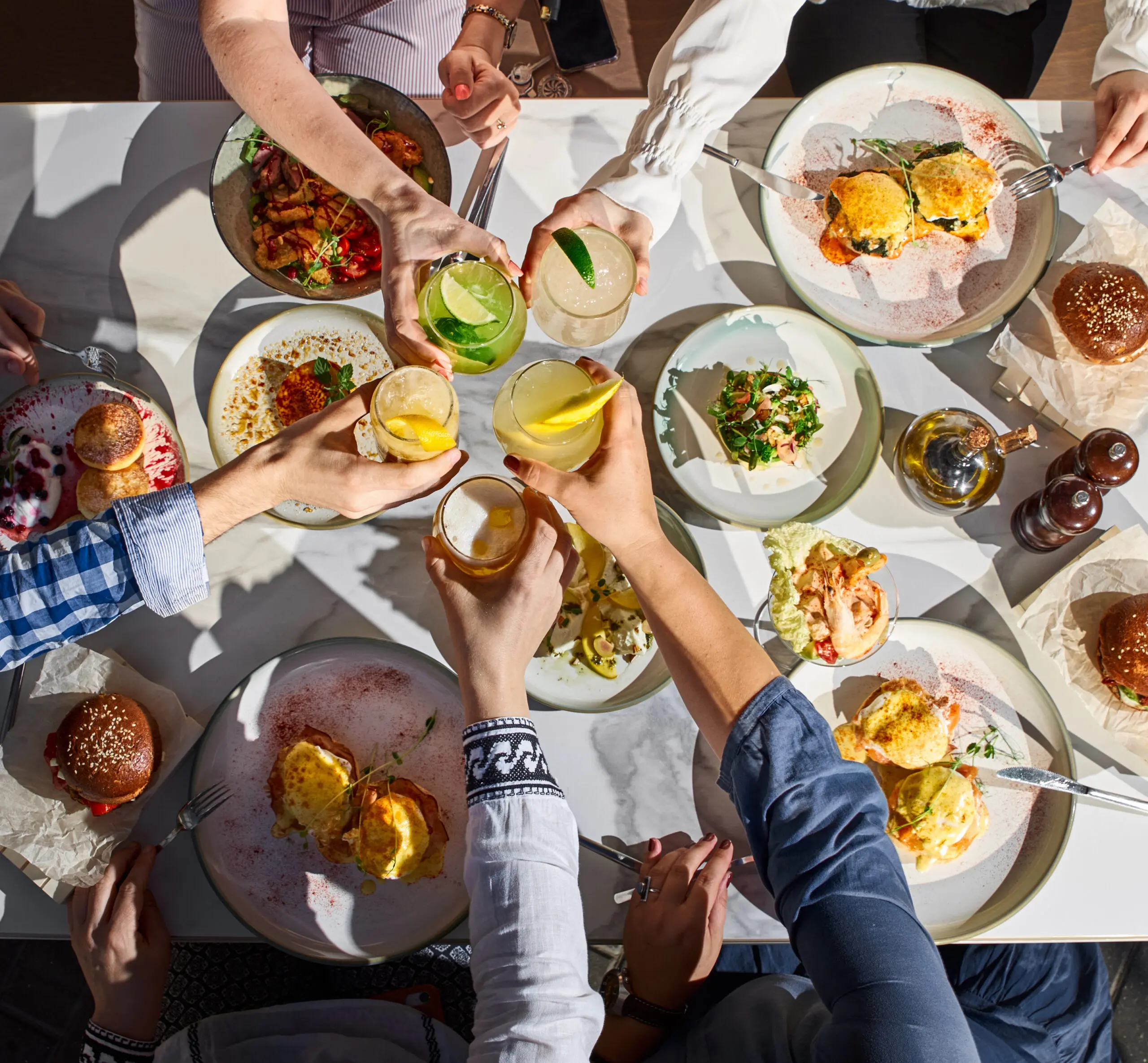 Group toasting drinks over a table full of shared dishes.