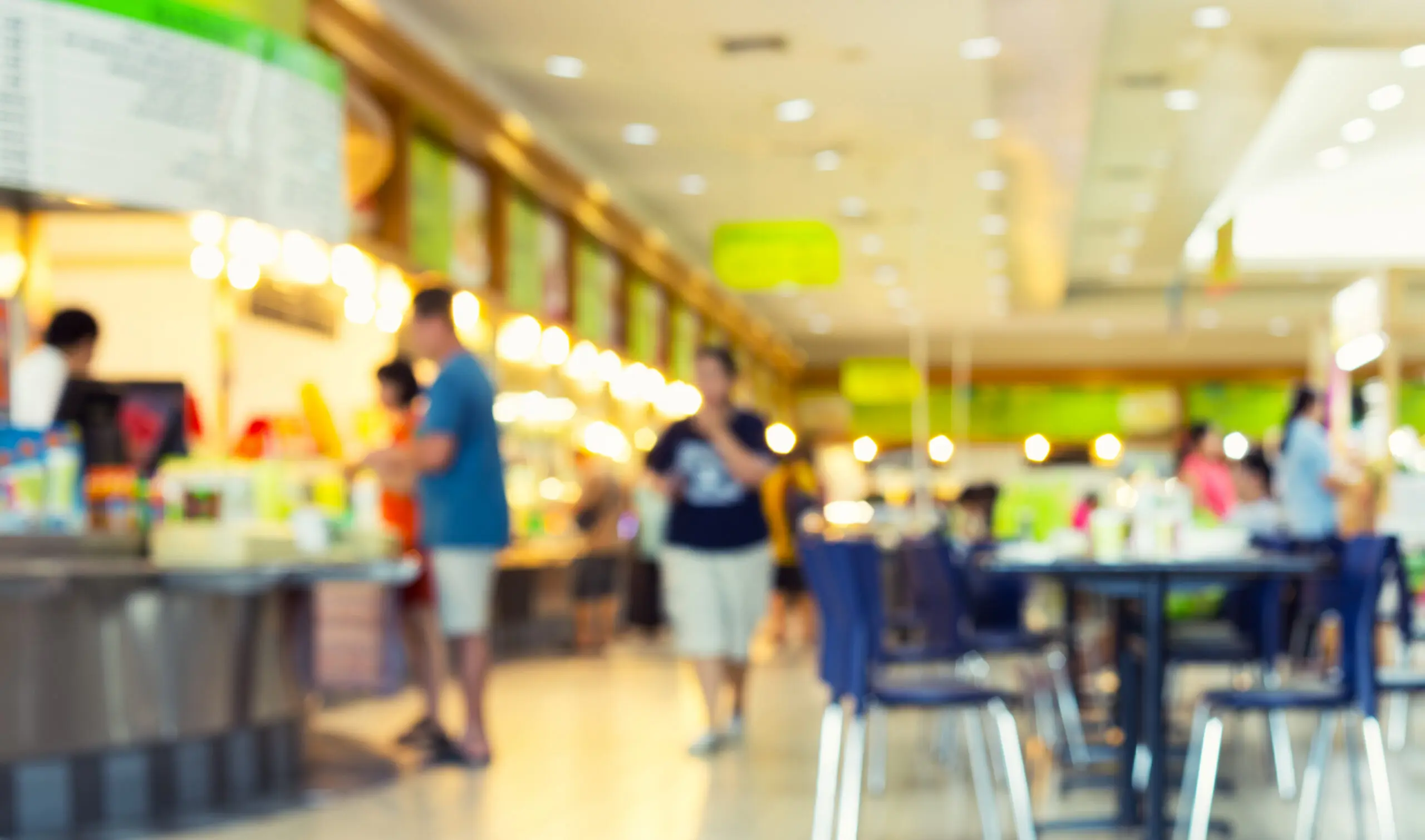 Blurred lunch room with green signs and people