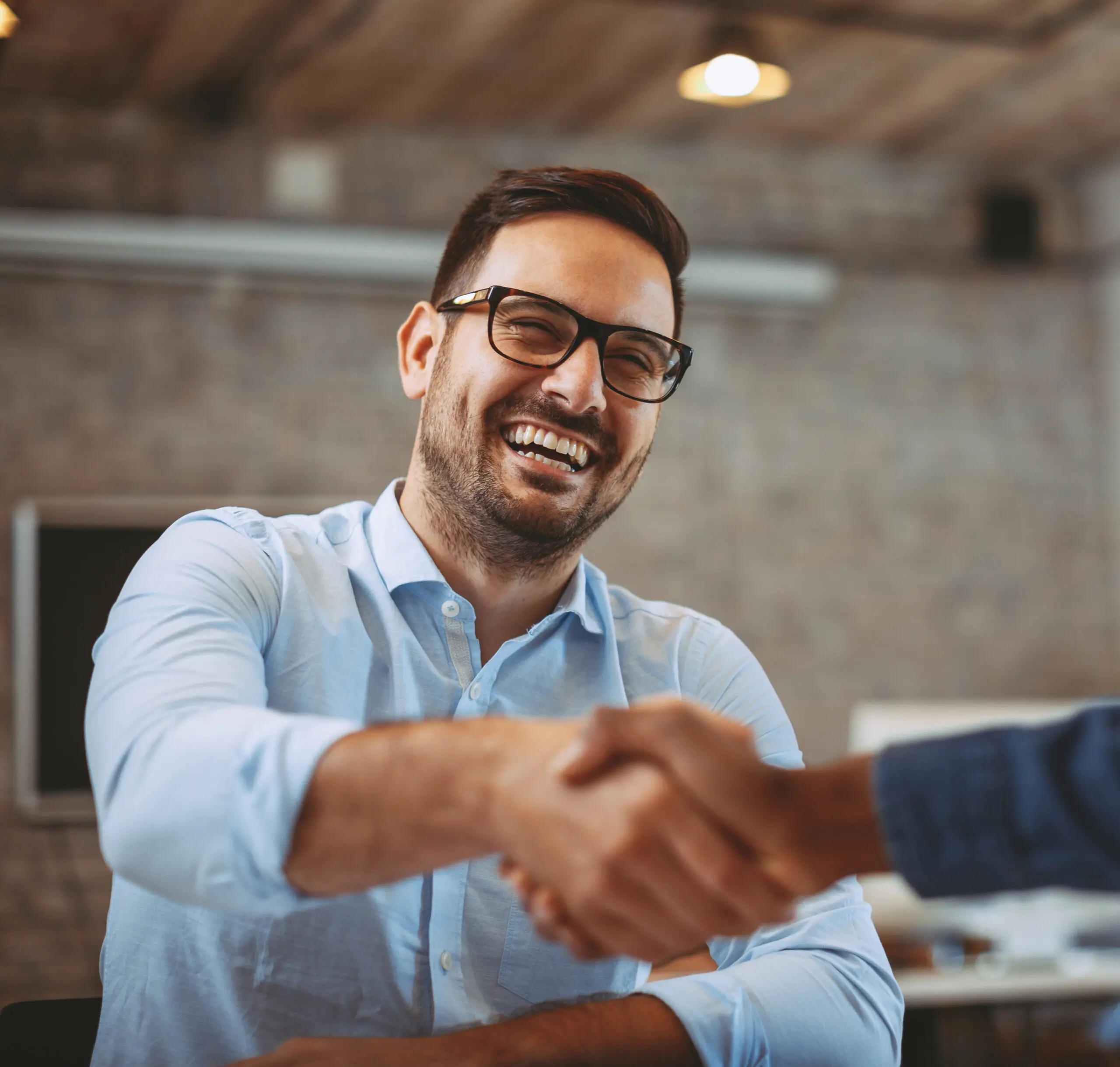 Two professionals shaking hands in an office , only one person smiling in photo