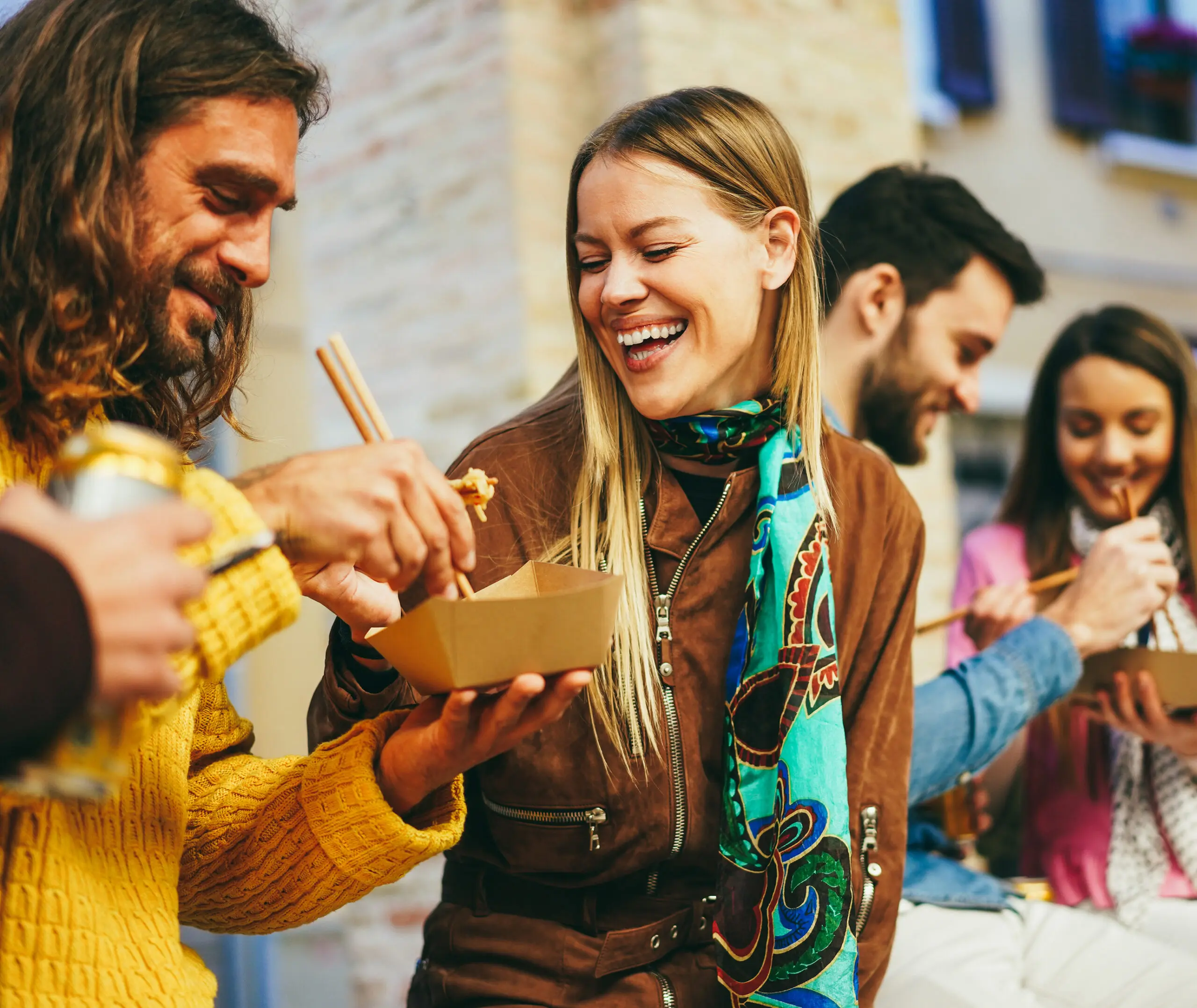 Man and woman talking and eating from takeout container with chopsticks