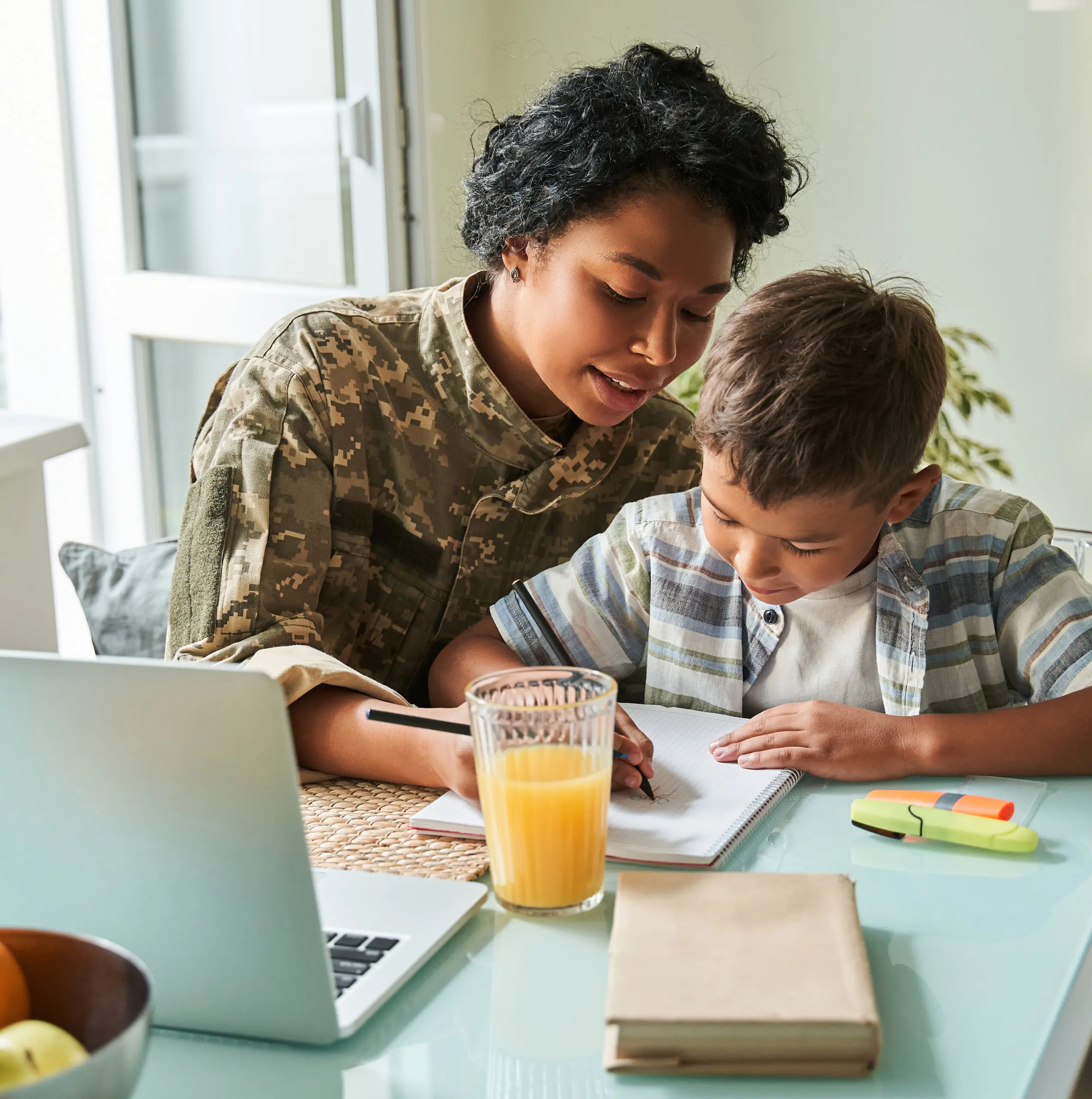 Service member assisting a child with schoolwork at home