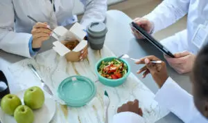 Healthcare professionals eating lunch during a break at a shared table.