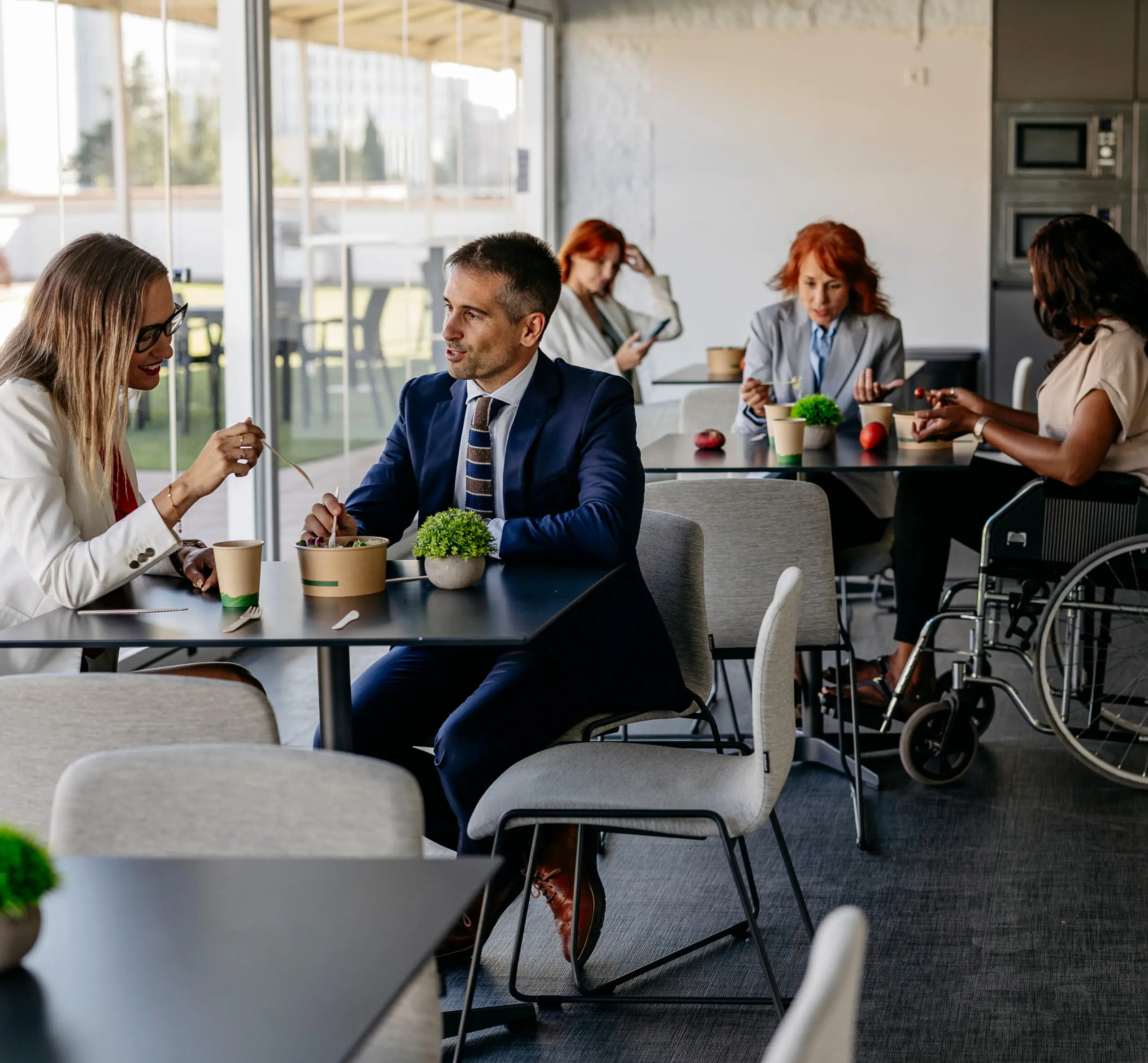 Woman and man seated in busy corporate office cafeteria.
