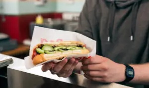 Sub sandwich being served at a quick-service concessions counter.