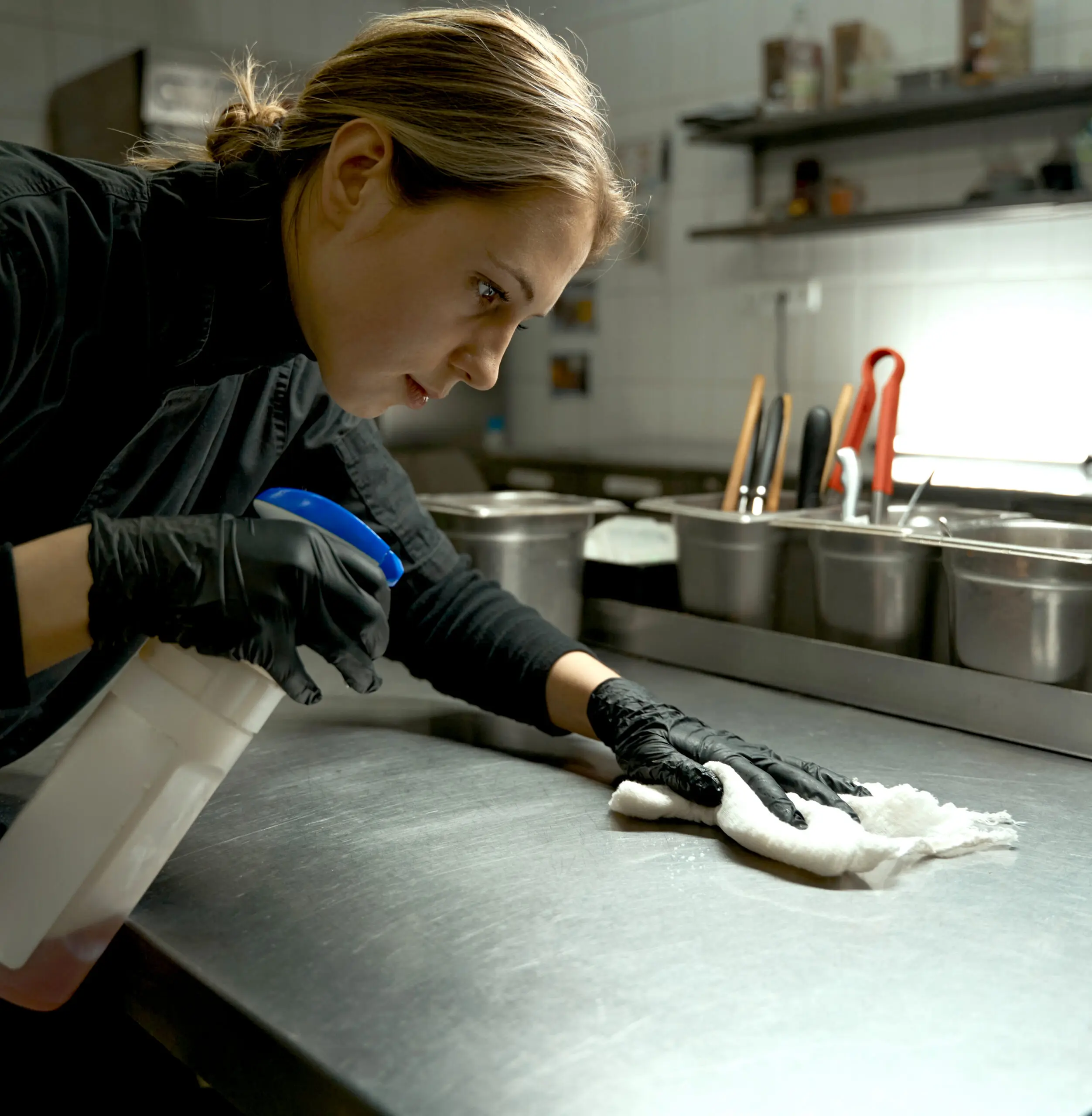 Restaurant chef sanitizes kitchen surfaces.