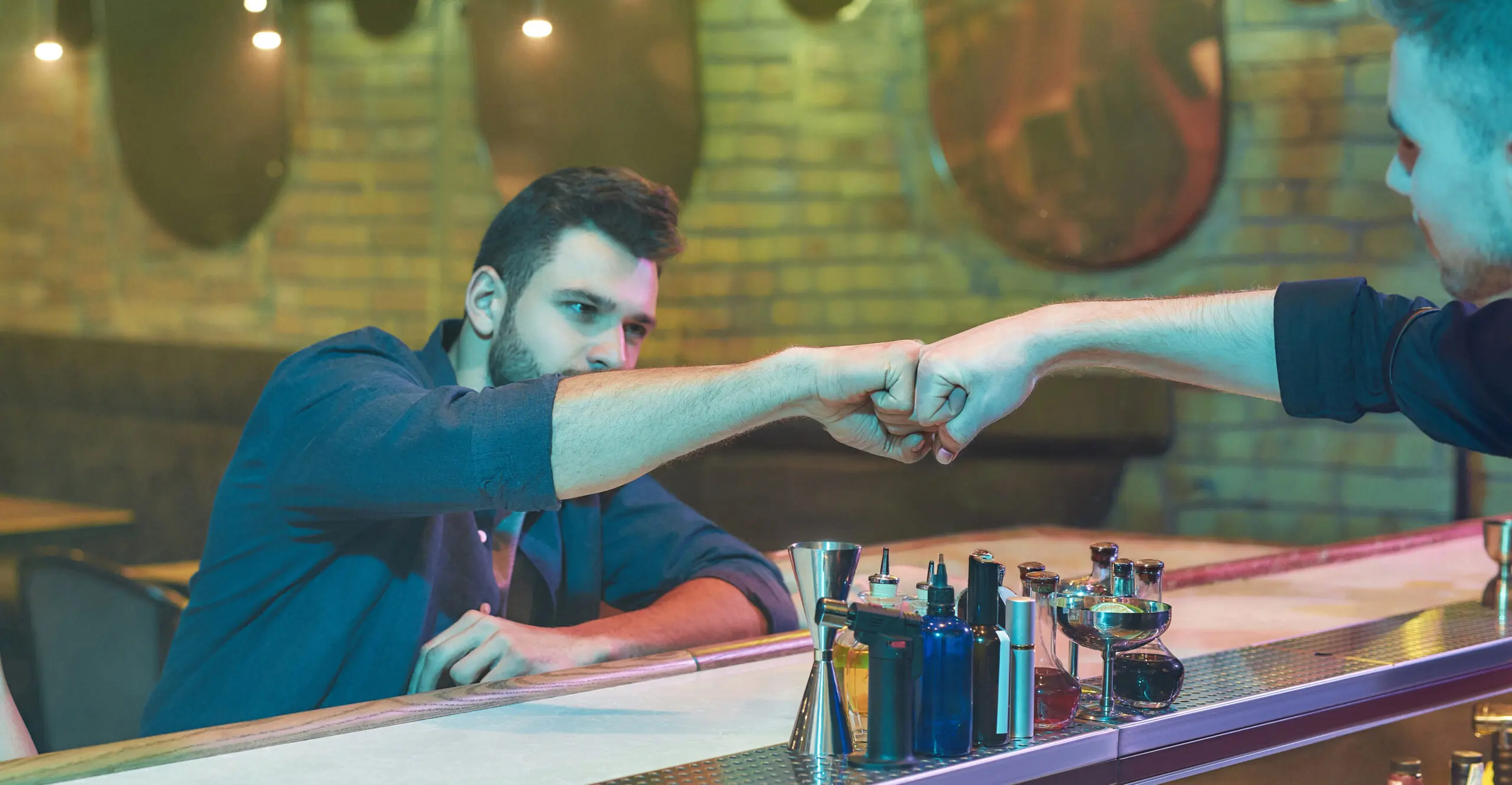Operator staff member and CORE sales team member fist bumping across a bar counter.