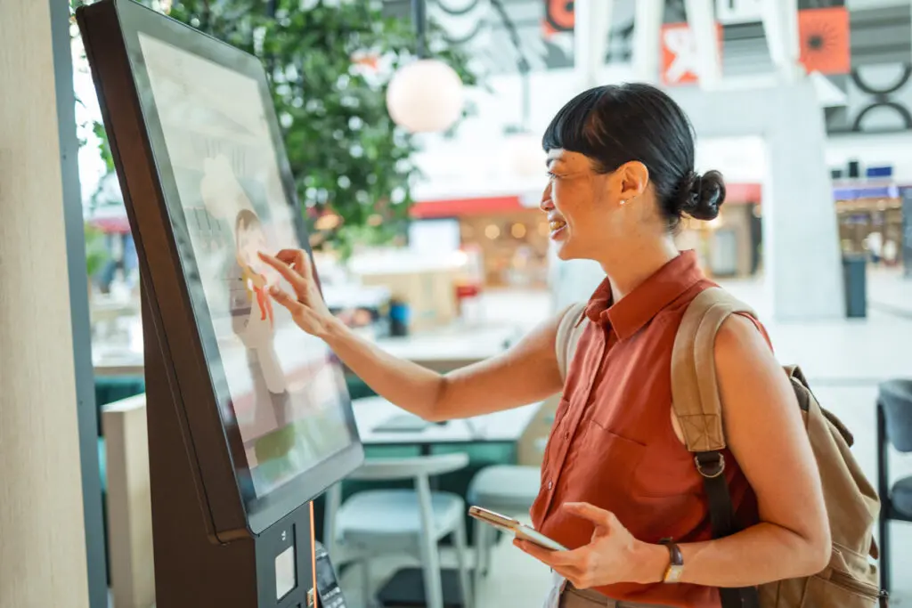 Customer using a touchscreen kiosk to place an order