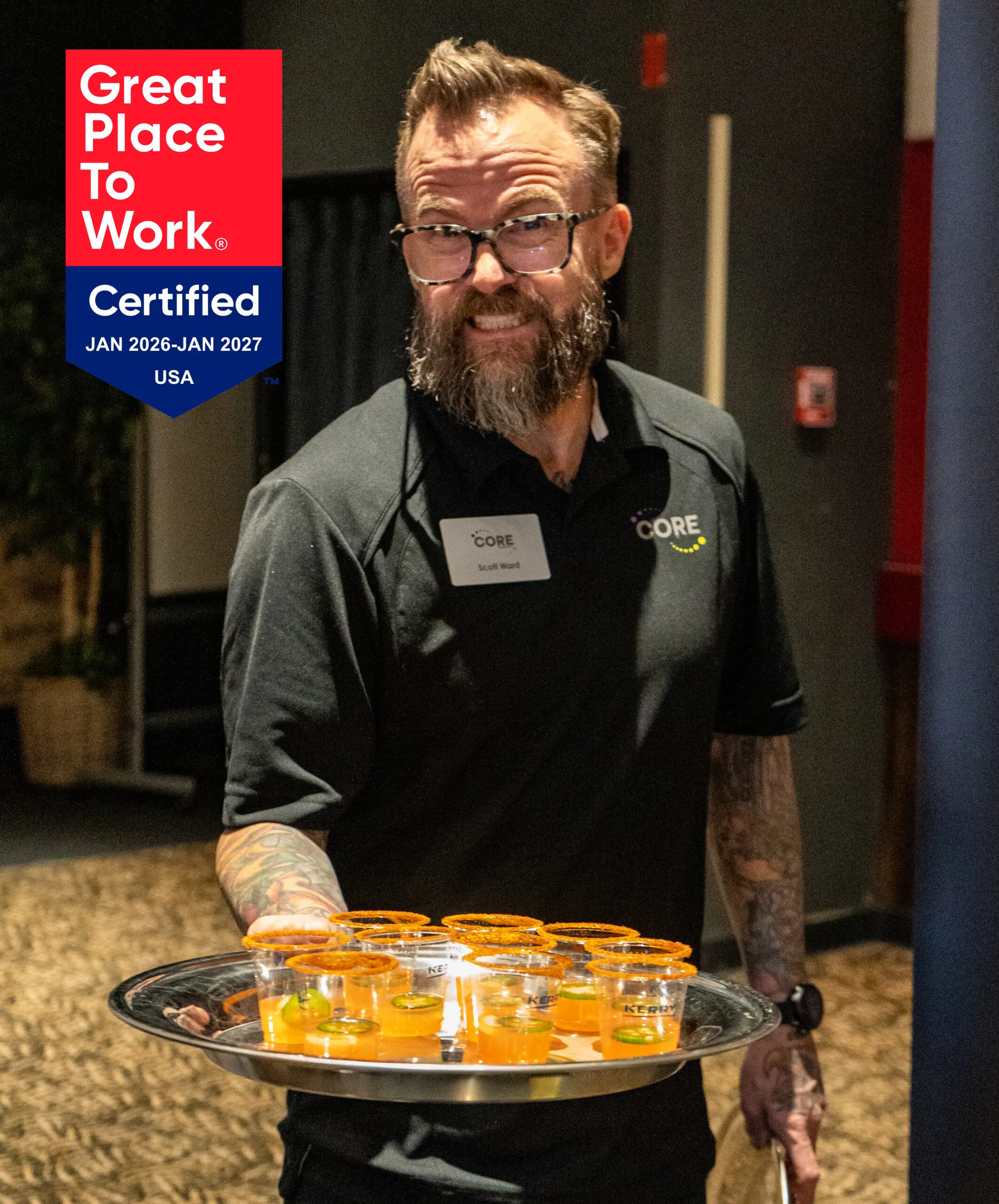 CORE team member smiles and offers a beverage sample.