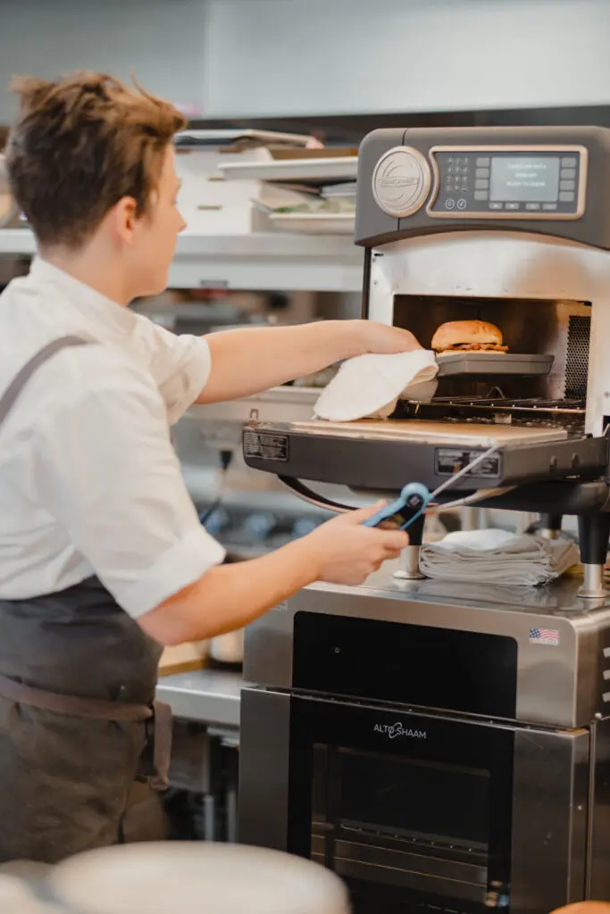 Foodservice professional placing a sandwich in a commercial oven